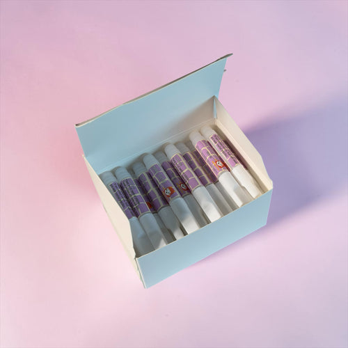 Nail Monsters professional adhesive nail glue pens in a light blue box on a pink background