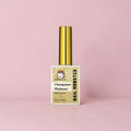 Nail Monsters Champagne Platinum gel polish bottle with a gold cap on a soft pink background.