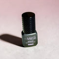 Nail Monsters Nomi Beauty Lab professional eyelash extension adhesive in a 5ml bottle with a textured black cap.