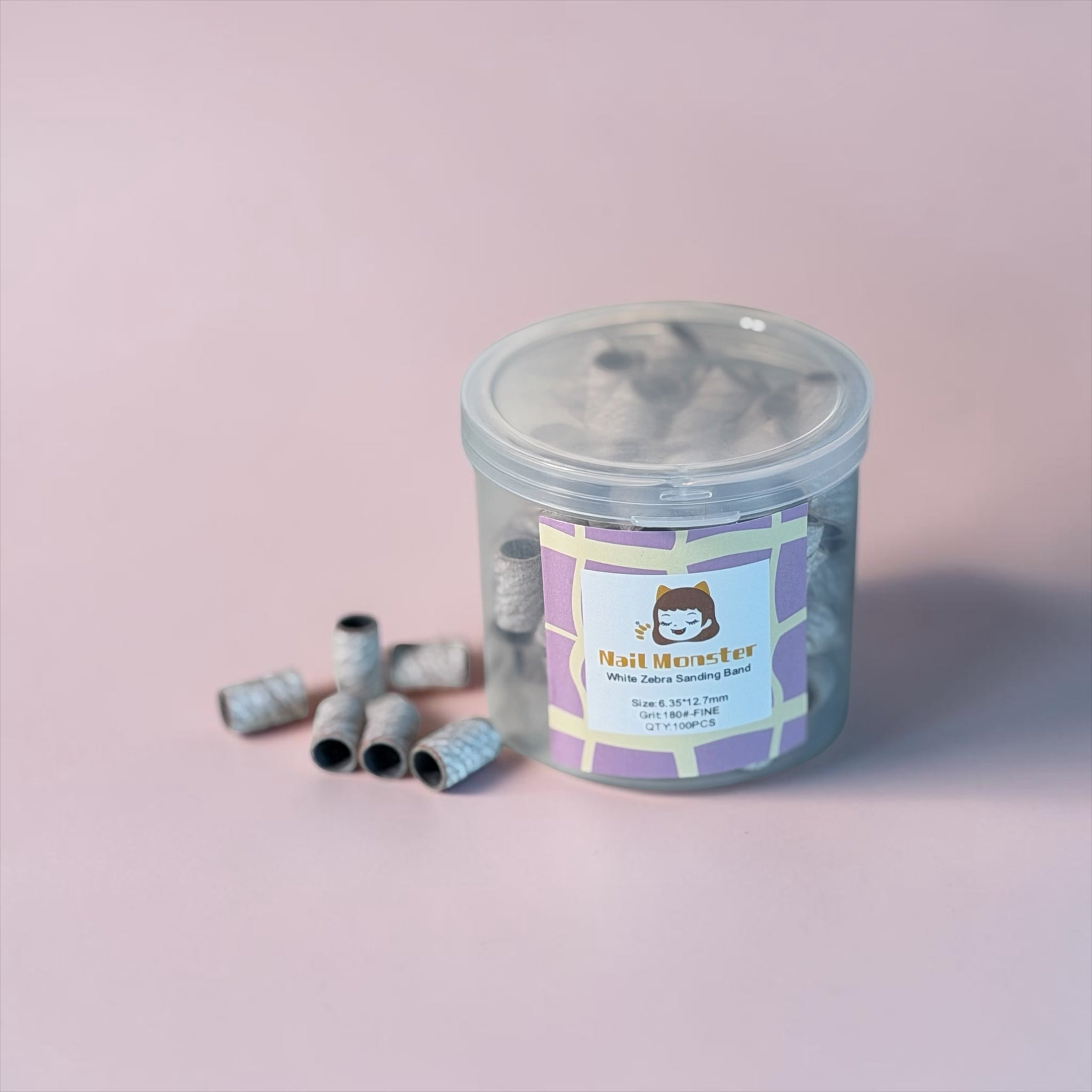 Nail Monsters 180-grit white zebra sanding bands in a clear storage jar for professional nail filing and buffing.