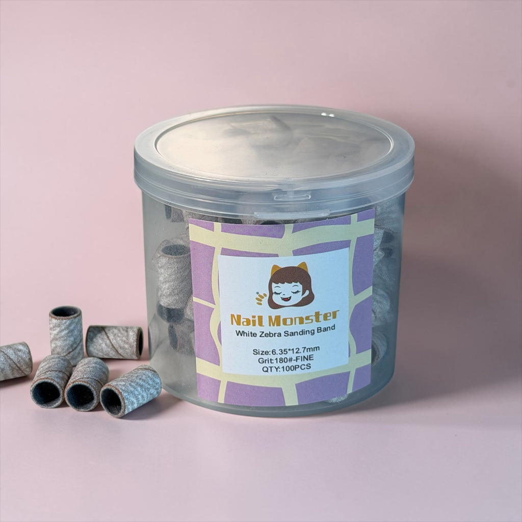 Nail Monsters 180-grit white zebra sanding bands in a clear storage jar for professional electric nail file use.